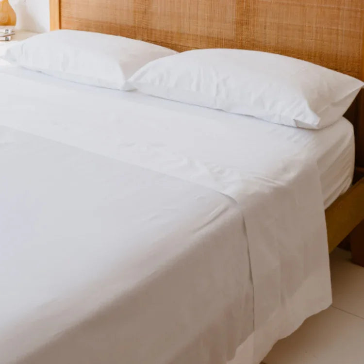 queen bed with rattan headboard and white sheets with white pillowcases